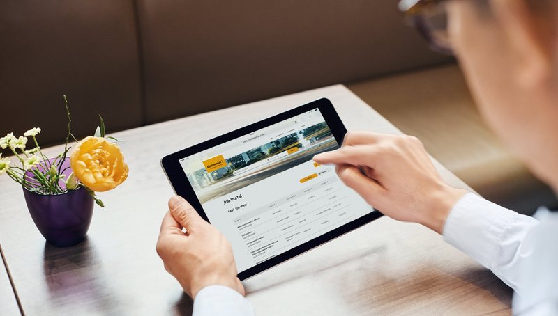 A person holds a tablet in their hand and searches the job portal for the right job.